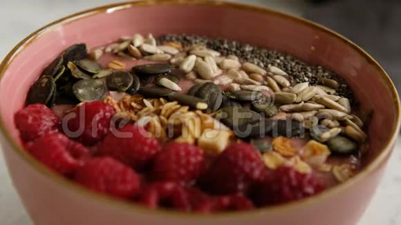 有人用格拉诺拉吃树莓冰沙碗种子用勺子吃辣椒关门素食早餐视频的预览图