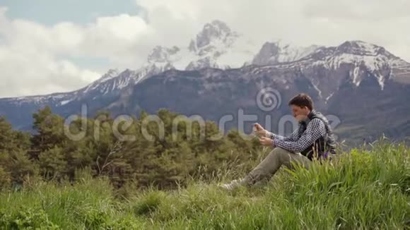 阳光明媚的一天穿着格子衬衫和背心的年轻人坐在一片绿色的草地上五彩缤纷的春天视频的预览图