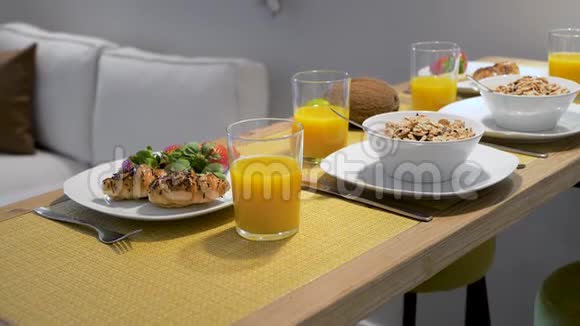 早餐包括玉米片新鲜草莓牛角面包和橙汁供一对夫妇在木桌上享用视频的预览图