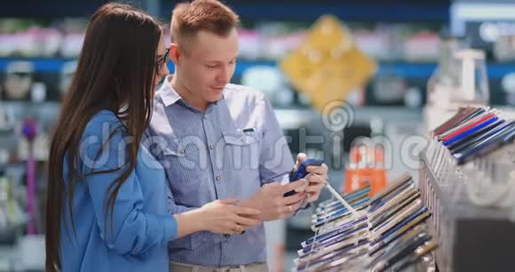 这对夫妇在电子商店里选择了一部手机带智能手机的展示视频的预览图