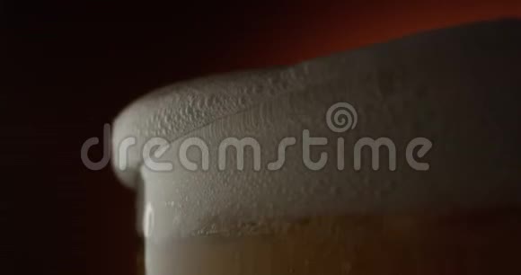 啤酒泡沫的宏观从陶陶背景拍摄的红色史诗玻璃中涌出视频的预览图