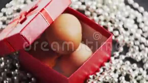 复活节三个鸡蛋放在一个红色的礼品盒里圆饰首饰特写慢动作白色背景视频的预览图