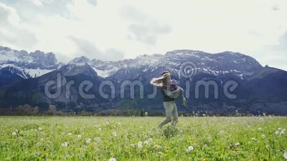 有魅力的情侣手牵着手在阿尔卑斯山的山地草地上旋转遥远的计划视频的预览图