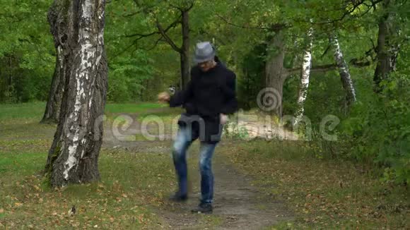 一个戴着帽子和外套的商人在树林里快乐地跳着舞轻轻地拍着脚视频的预览图