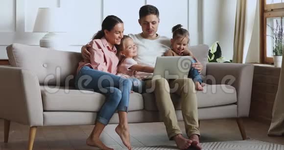 一家四口在沙发上用手提电脑做电视游戏视频的预览图