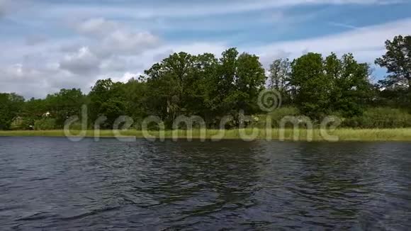 湖岸绿树上美丽的景色深蓝色的水面和绿色的树木蓝天上有白云的背景瑞典视频的预览图