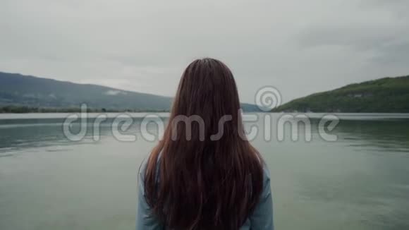 长长的黑发女人站着欣赏风景秀丽的山景和湖景视频的预览图