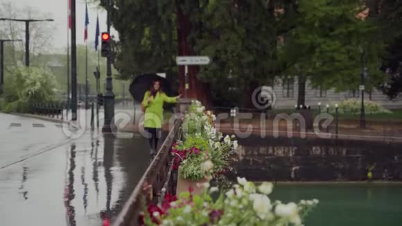 快乐的女孩穿着亮黄色的外套带着雨伞在雨天穿过安纳西的一条运河穿过大桥视频的预览图