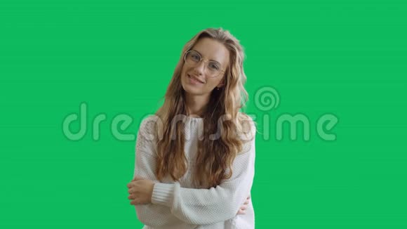 戴眼镜的聪明女孩在绿色屏幕背景下看相机的肖像一个聪明的少年微笑着视频的预览图