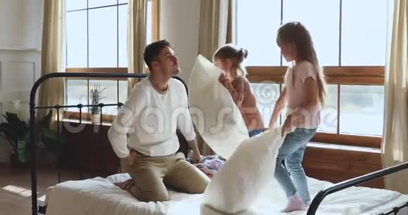 有趣的快乐爸爸和女儿在床上玩枕头大战视频的预览图