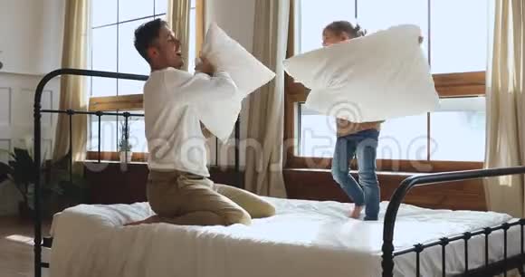 无忧无虑的小女儿和爸爸在床上玩枕头大战视频的预览图