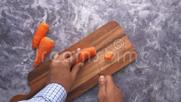 男子手切胡萝卜在砧板上的俯视图视频的预览图