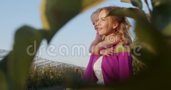 幸福的家庭日落时带着女儿在果园里微笑的女人4K视频的预览图