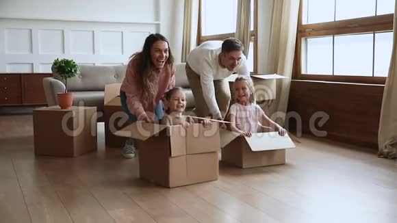 快乐的父母带着小孩推纸板箱慢动作视频的预览图