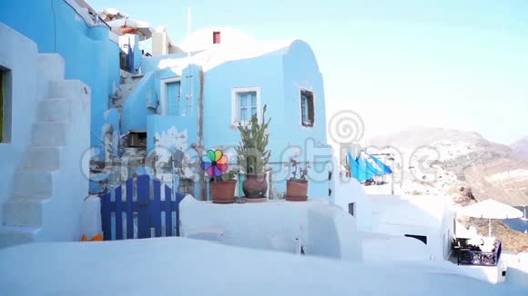 五颜六色的风车移动在一个典型的希腊建筑前面奥亚圣托里尼希腊视频的预览图