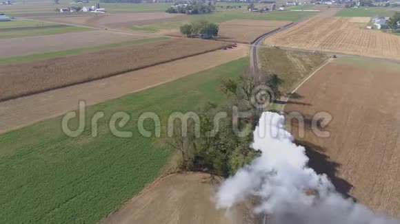 蒸汽火车吹烟和蒸汽沿着乡村旅行的鸟瞰图视频的预览图