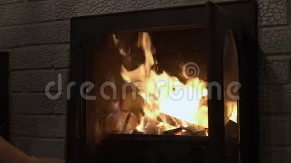 一个男人正在燃烧的家庭壁炉里搅动原木特写镜头4k视频的预览图