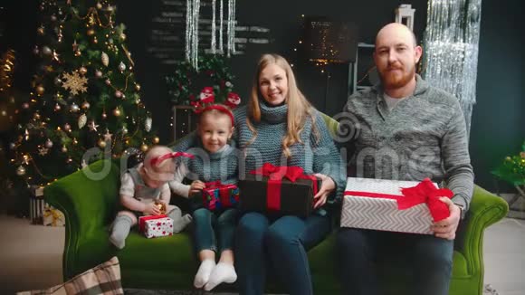 圣诞节概念幸福的家庭坐在沙发上拿着礼物孩子们互相玩耍视频的预览图