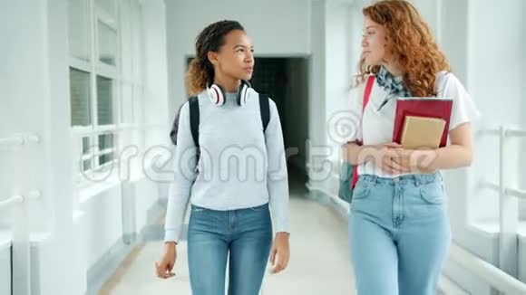 快乐的年轻女士在大学大厅里慢悠悠地走着做着击掌视频的预览图