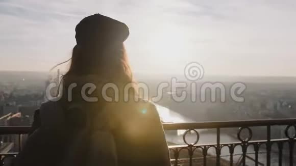 后景年轻快乐的美丽旅游女子背着背包观看巴黎日落在埃菲尔铁塔顶部缓慢的运动视频的预览图