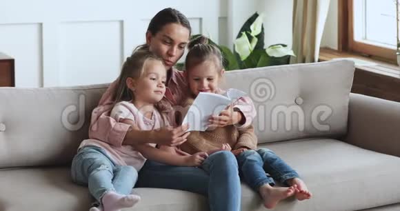 爱看书的年轻妈妈拥抱可爱的孩子们的女儿视频的预览图