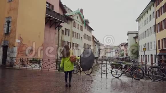 美丽的幸福女孩走在老建筑附近的桥上玩着她的黑色雨伞雨天Brunette视频的预览图