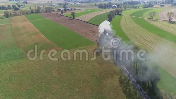 一台老式的蒸汽机经过农田吹烟和蒸汽的空中景色视频的预览图