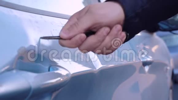 手用螺丝刀或大钉子刮擦车辆车门上的油漆表面特写罪犯从事视频的预览图