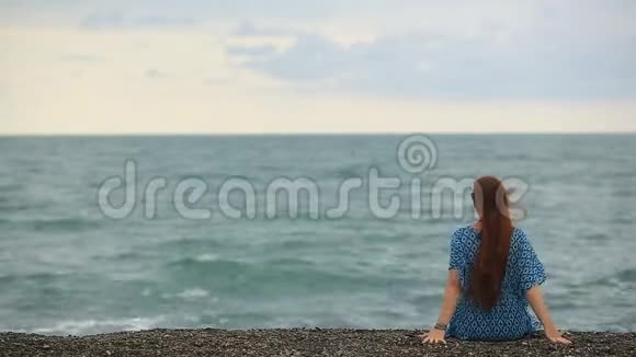 生活方式美丽的女人坐在海滩上放松女人头发在风中摇曳视频的预览图