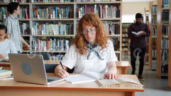在图书馆学习的人使用书籍和笔记本电脑阅读的慢动作视频的预览图