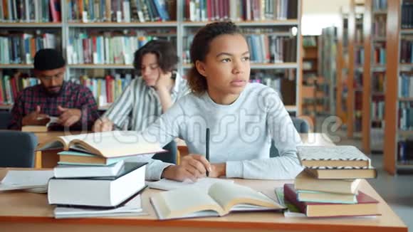 疲惫的非裔美国女孩在大学图书馆读书视频的预览图