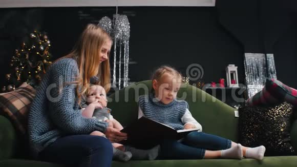 新年妈妈带着孩子坐在沙发上看书爸爸带着礼物来视频的预览图