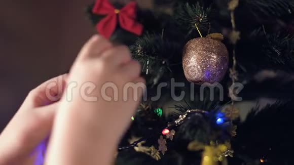 一个小女孩的手的特写装饰了一棵新年树把玩具挂在树枝上视频的预览图