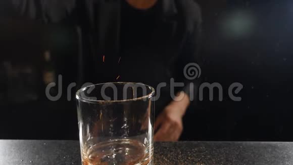 酒保点燃鸡尾酒在黑色背景的酒精饮料中燃烧肉桂慢条斯理的鸡尾酒杯里的火焰视频的预览图