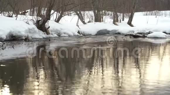 河中傍晚太阳的倒影河的雪岸流动的水经过融化的冰雪视频的预览图