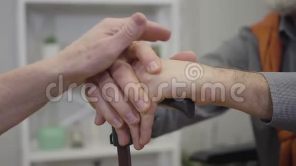 特写的老白种人的双手放在男性手臂上手里拿着手杖老年退休人员互相支持视频的预览图
