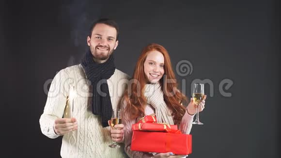 年轻的幸福夫妇站在工作室拿着火花和礼物微笑着看着相机视频的预览图