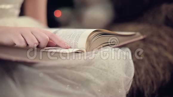 特写一个身穿节日礼服的金发小女孩手里拿着一本书坐在背景软玩具旁边视频的预览图