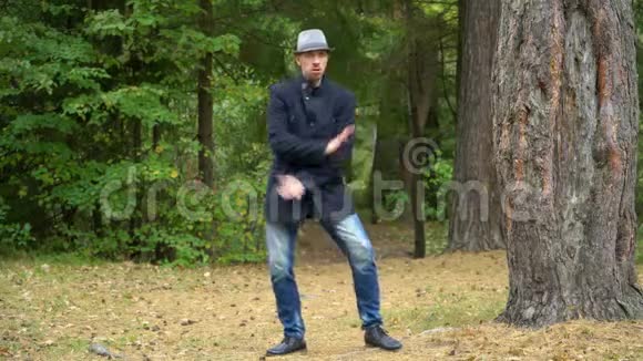 穿着帽子和外套的商人在树林里快乐地跳迪斯科视频的预览图