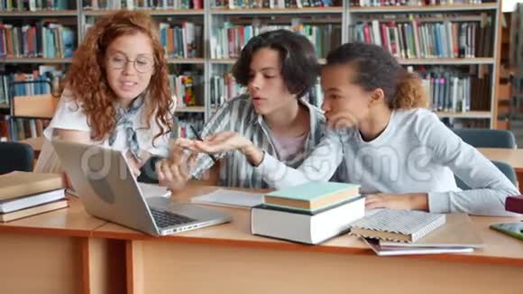 利用笔记本电脑和书籍在图书馆项目工作的女生和男生视频的预览图