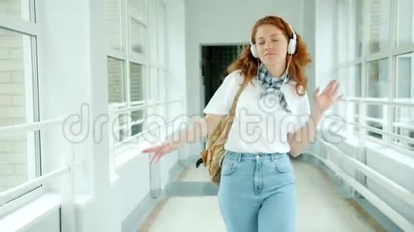 戴着耳机的快乐少年在学校大厅里享受音乐舞蹈视频的预览图