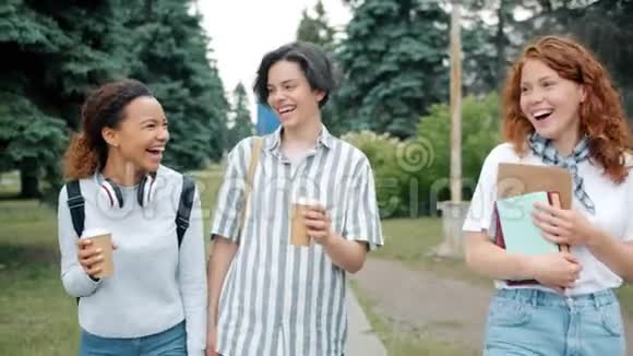 快乐的年轻人笑着玩着带着书走到户外去喝咖啡视频的预览图