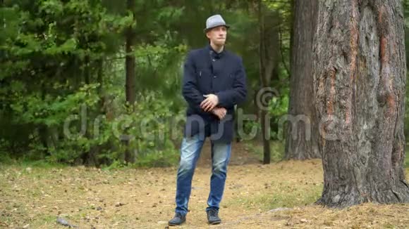 一个戴着帽子和外套的商人站在树林里就像约翰特拉沃尔塔一样视频的预览图