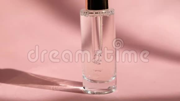 将血清滴在透明玻璃瓶中放在粉红色背景和女人手上特写护肤美容美容视频的预览图