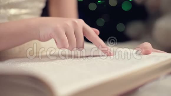 特写一个身穿节日礼服的金发小女孩手里拿着一本书坐在背景软玩具旁边视频的预览图