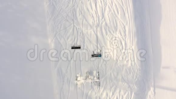 在山地度假胜地雪坡上无人机飞过移动的滑雪电梯顶部空中观景滑雪电梯运送滑雪者和雪艇视频的预览图