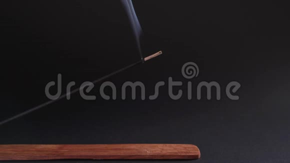 在美丽的木架上燃烧在黑色的背景上燃烧健康繁荣的芳香疗法的概念视频的预览图