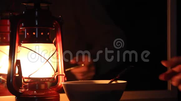 手拿一勺蜂蜜放在煤油灯的背景上视频的预览图
