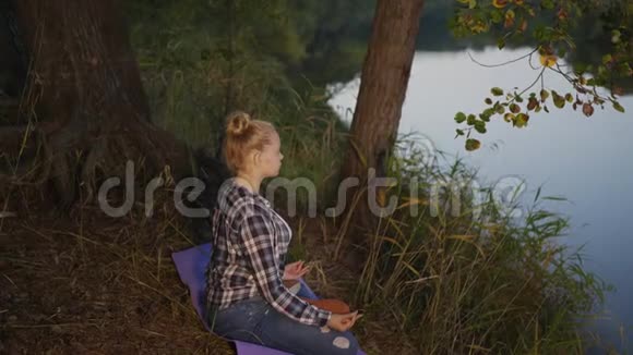 晚林江岸少女静思莲姿在河边练习瑜伽冥想的女孩视频的预览图