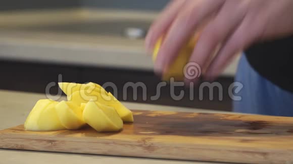 一个女人在锅的背景上用刀把生的新鲜黄土豆切成碎片煮自制的食物视频的预览图
